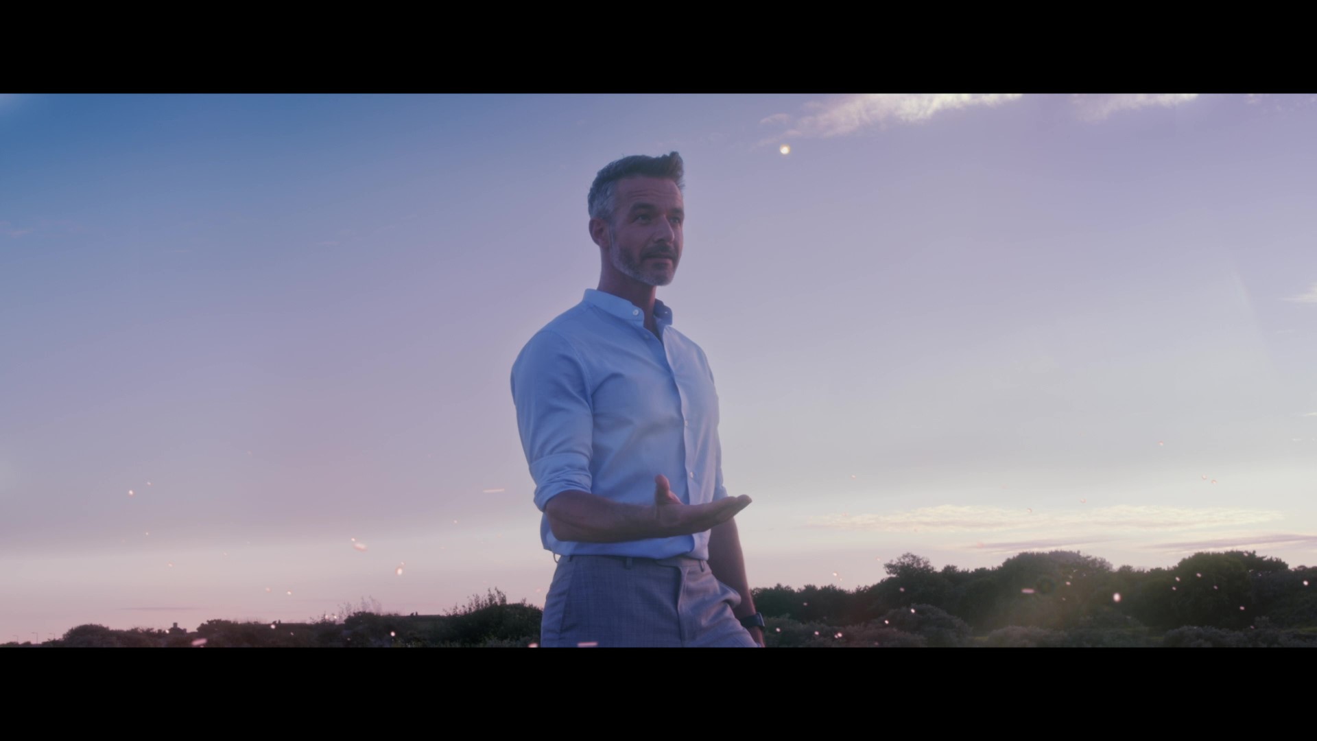 A man at dusk mid-gesture, still from the brand film