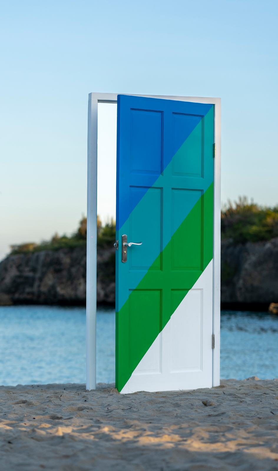A brand-painted door standing on a Caribbean beach